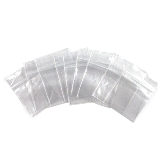 Stacked clear plastic bags, semi-transparent, uniformly sized, visible seal at the opening, grouped in a pack of 100